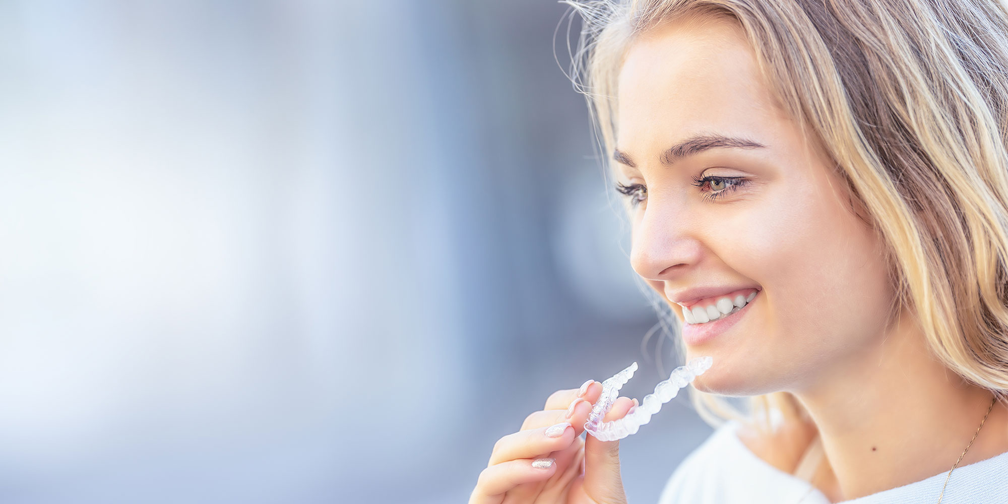 blond woman putting on Invisalign