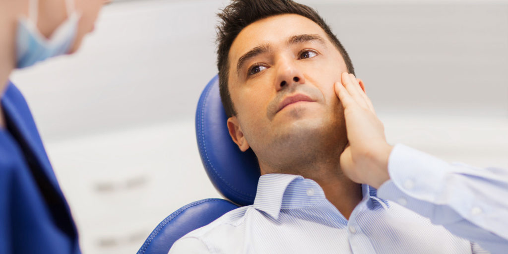 man dental chair tooth pain