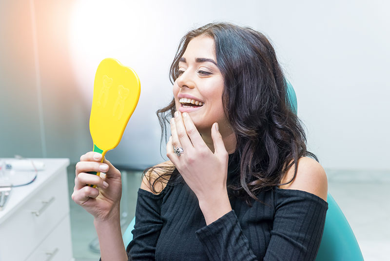 woman checking teeth mirror